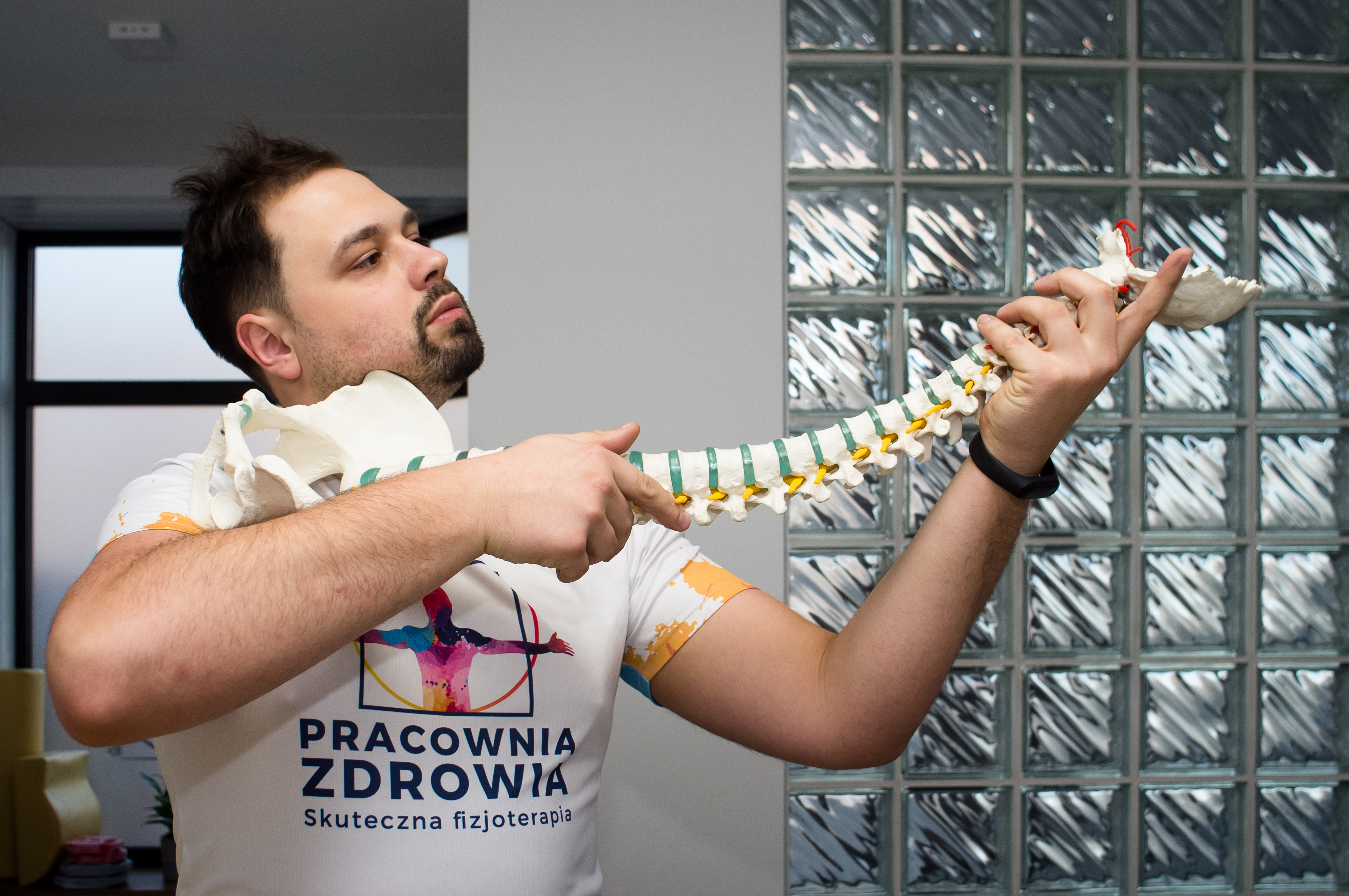 fizjoterapeuta, rehabilitacja zabrze, kręgosłup, Michał Jureczek trzyma model kręgosłupa